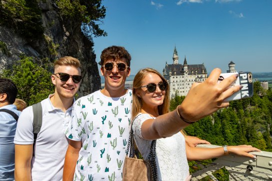 Group of friends taking a selfie in front of Castle Neuschwanstein